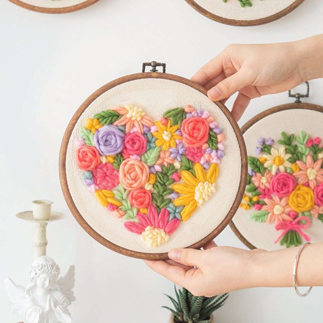 Puddingcase punch needle kit with a heart-shaped floral design in a wooden hoop, ideal for DIY embroidery crafts.